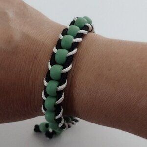 Macrame bracelet in black and white tone with plastic balls in green tone.